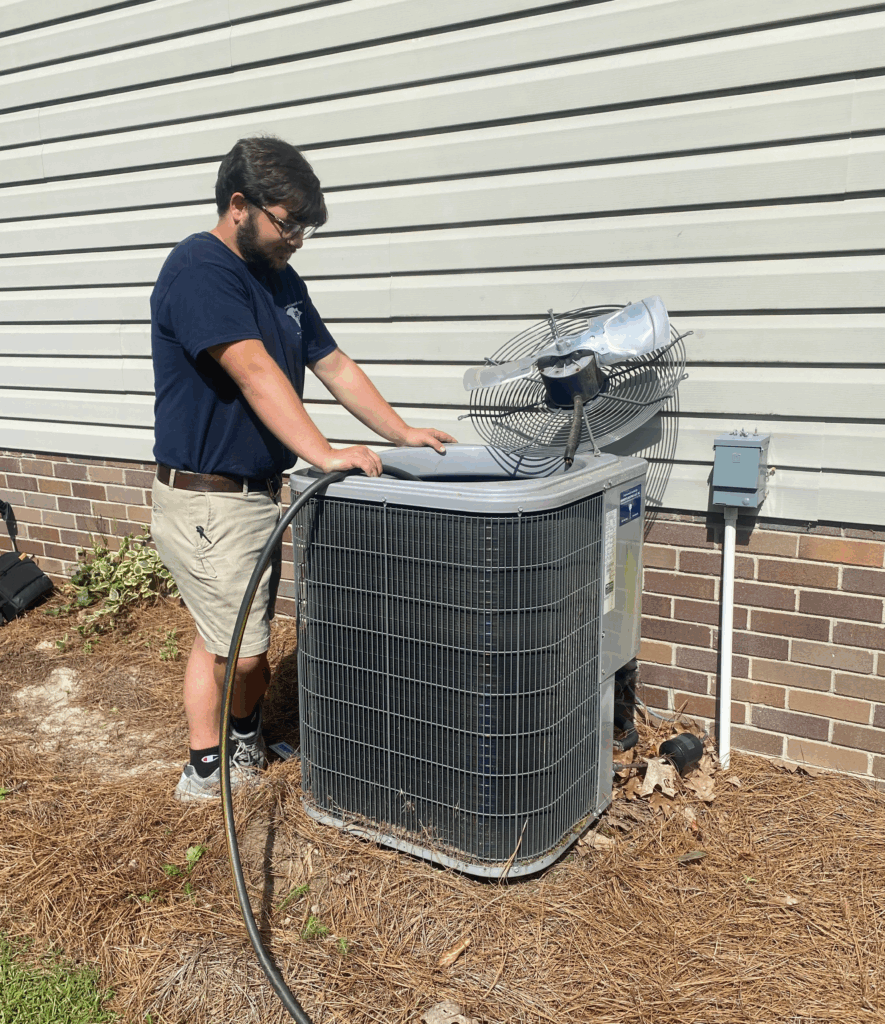hvac technician Russ Williams inspecting air conditioning unit outside home
